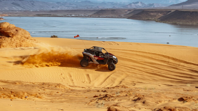 CanAm UTV kicks up sand while off-roading at Sand Hollow near the lake, showcasing adventure at Southern Utah’s scenic sand dunes.